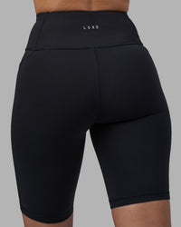 Woman wearing Rep Ultra High-Rise 9" Short Pockets - Black-Power Cobalt | Model:Rhiley | Size:S