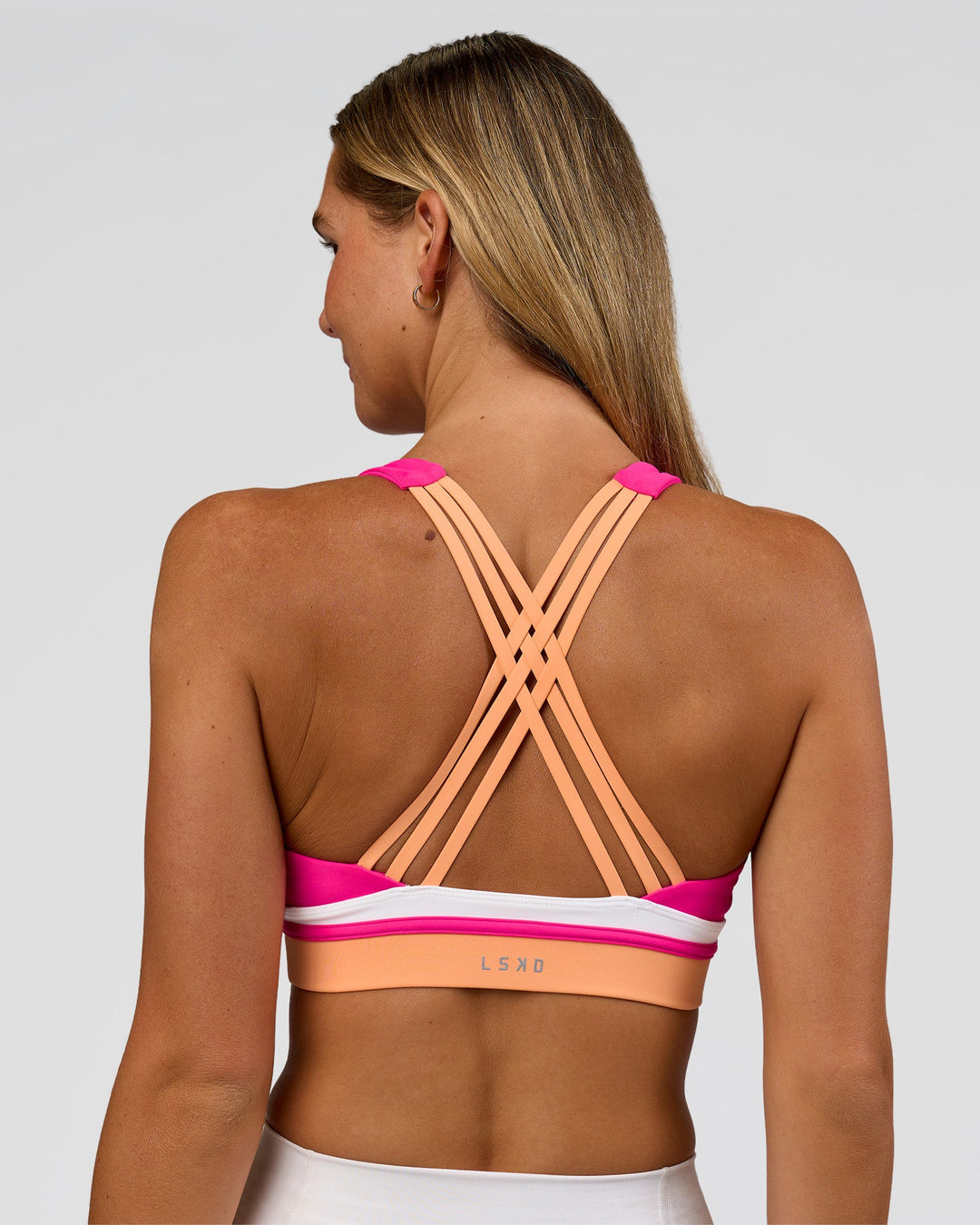 Woman wearing Revitalise Flash Sports Bra - Ultra Pink-Cantaloupe-White | Model:Amity | Size:S
