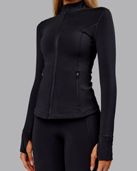 Woman wearing Stride Thermal Zip Through Jacket - Black | Model:Ella | Size:S