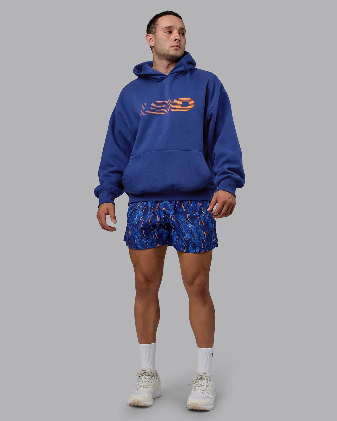 Man wearing Unisex Motion Hoodie Oversize - Galactic Cobalt-Vibrant Orange