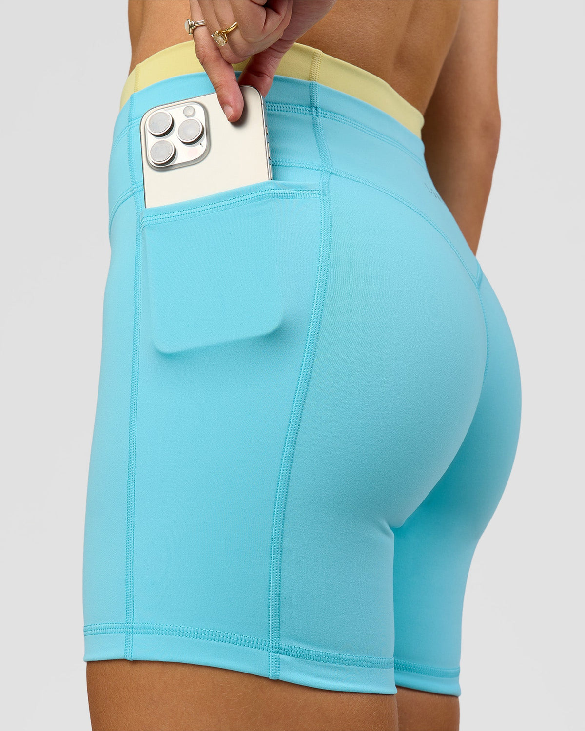 Woman wearing Lume Fusion Mid-Rise V Contour 6" Short Pockets - Baltic Sea-Lemon | Model:Grace | Size:XS - view 1