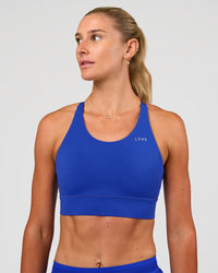 Woman wearing Accelerate Split Strap Sports Bra - Electric Indigo | Model:Emelia | Size:XS