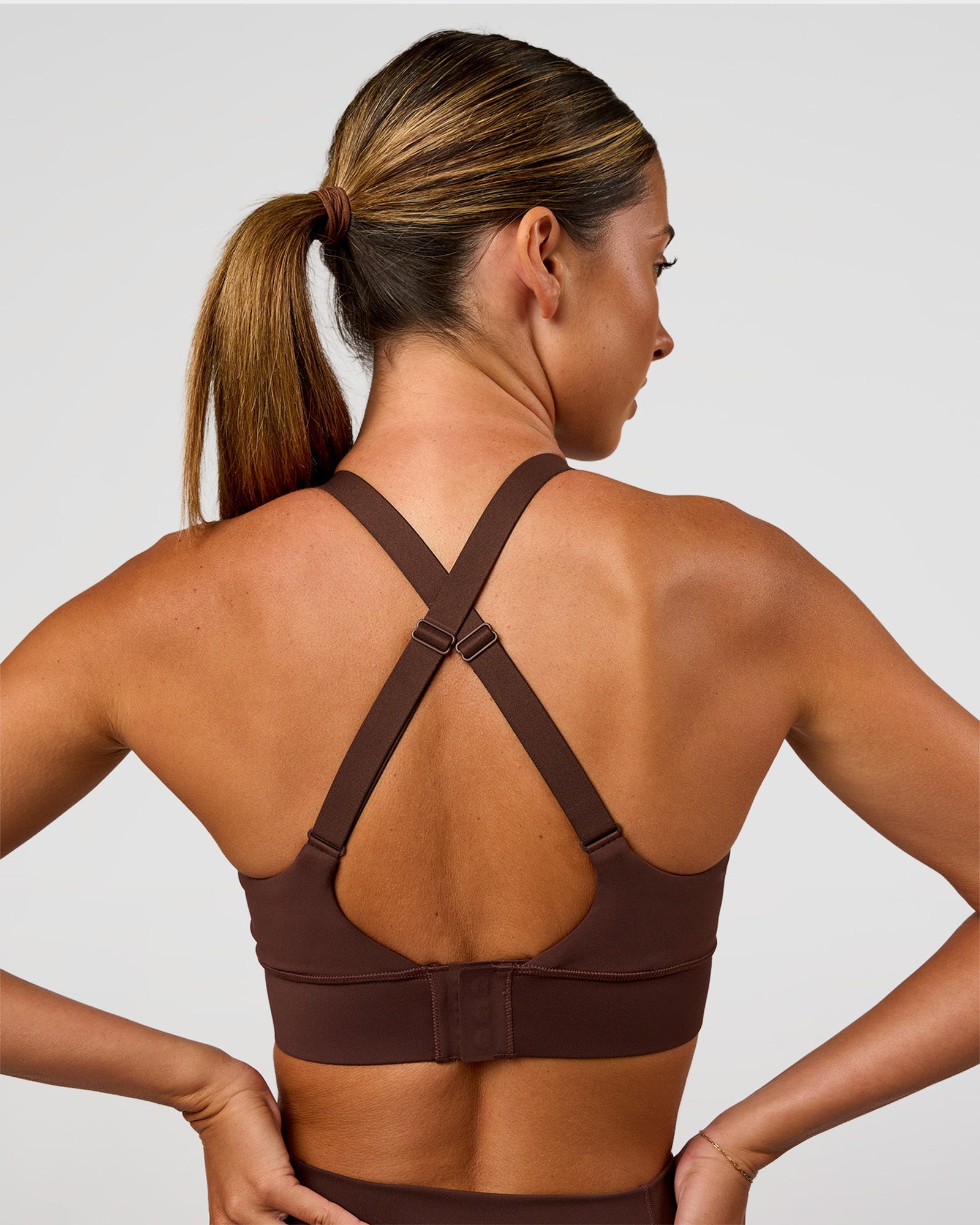 Woman wearing Accelerate Sports Bra - Hot Chocolate | Set:true | Angle:back | Model:Charli | Size:XS