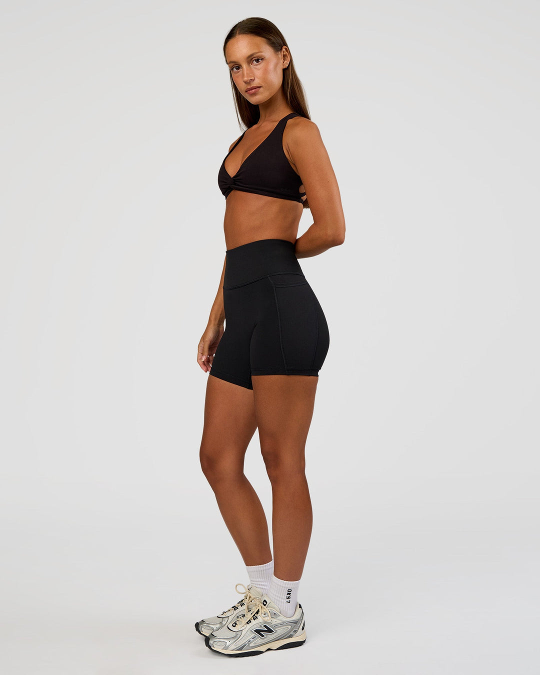 Woman wearing Aspire Twist Sports Bra - Black | Model:Brylee | Size:XS