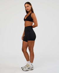Woman wearing Aspire Twist Sports Bra - Black | Model:Brylee | Size:XS