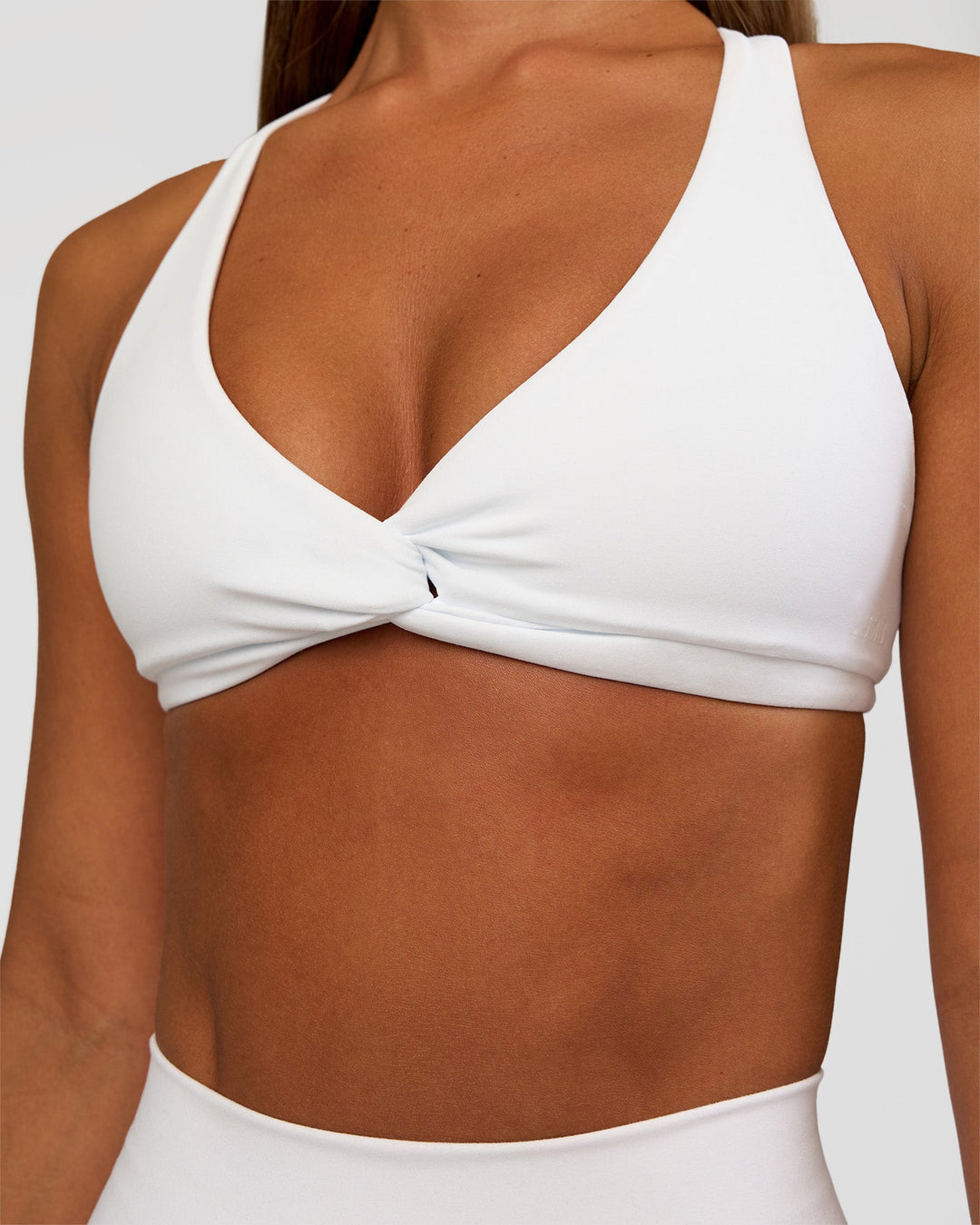 Woman wearing Aspire Twist Sports Bra - White | Model:Brylee | Size:XS