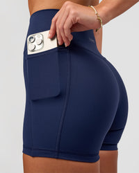 Woman wearing Fusion Ultra High-Rise 4" Short Pockets - Future Navy | Model:Issy | Size:XS