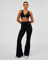Woman wearing Fusion V-Contour High-Rise Flared Legging Pockets - Black | Model:Charli | Size:XS