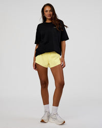 Woman wearing High Run FLXCotton Oversized Tee - Black-Yellow Fizz | Model:Kirstyn | Size:XS