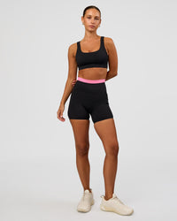 Woman wearing Liberate High-Rise 4" Short Pockets - Black-Candy Pink | Model:Brylee | Size:XS