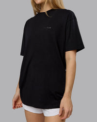 Woman wearing RUN CLUB FLXCotton Tee Oversize - Black-Reflective | Model:Emilie | Size:XS