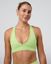 Woman wearing Stamina Sports Bra - Solar Lime | Set:true | Angle:front | Model:Emelia | Size:XS