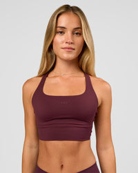 Woman wearing Twist Long Line Sports Bra in Cherry Lacquer | Model:Issy | Size:XS