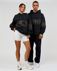 Duo wearing A-Team Oversized Hoodie - Caviar-Onyx | Model:Bianca | Size:XS | Model:Albert | Size:M | Thumbnail Index: 1