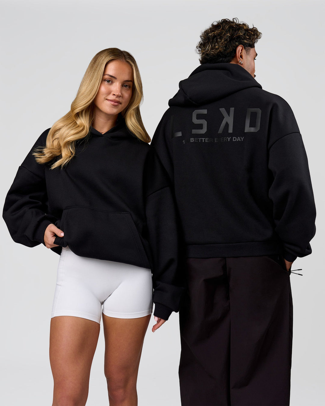 Duo wearing Tonal Legacy Boxy Hoodie - Black-Black | Model:Issy | Size:XS | Model:Xav | Size:L - view 4
