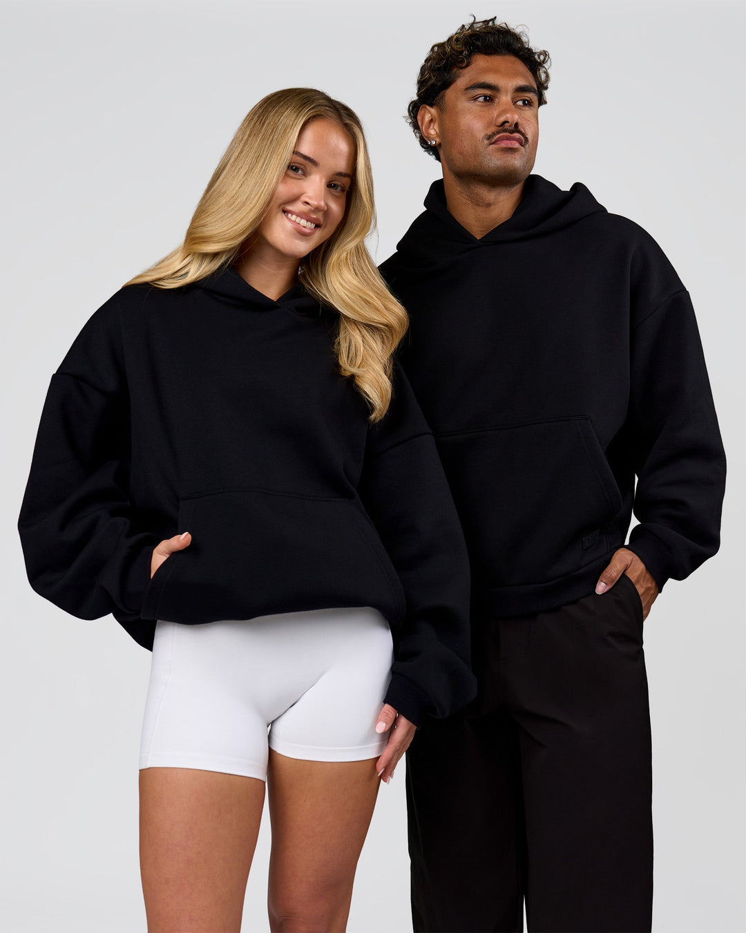 Duo wearing Tonal Legacy Boxy Hoodie - Black-Black | Model:Issy | Size:XS | Model:Xav | Size:L - view 7