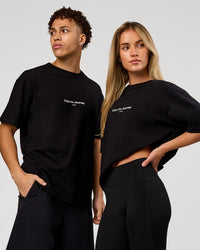 Duo wearing VS1 Enjoy The Journey FLXCotton Oversize Tee - Black | Model:Issy | Size:XS | Model:Leandro | Size:M | Thumbnail Index: 0