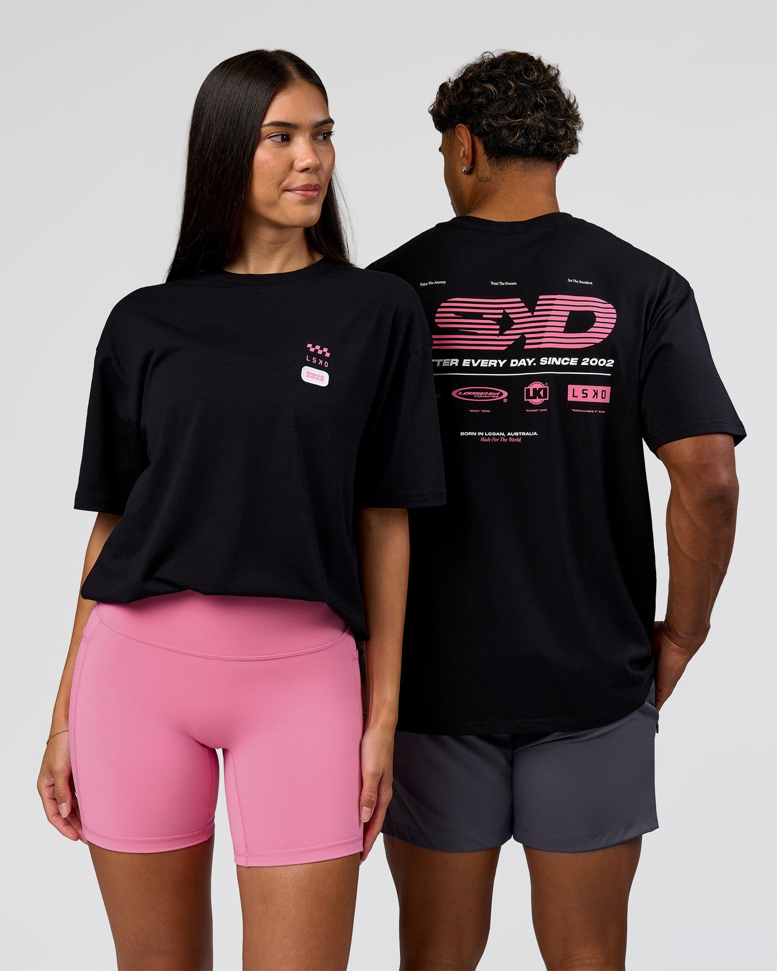 Duo wearing Archive FLXCotton Oversized Tee - Black-Candy Pink | Model:Rhiley | Size:XS | Model:Xav | Size:L