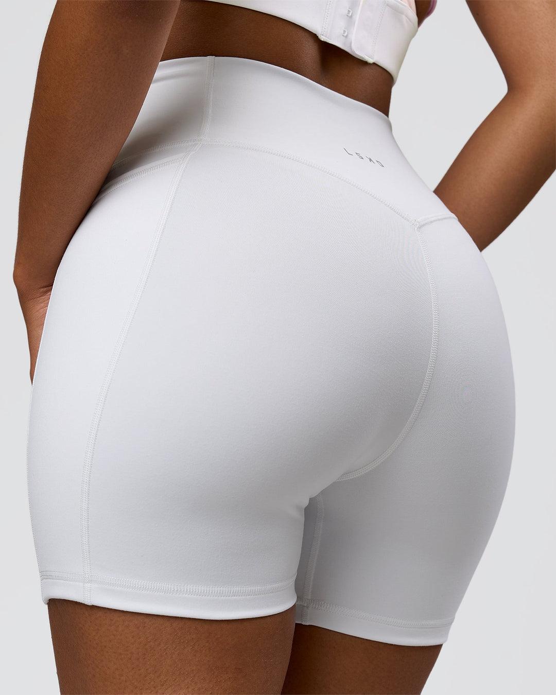Woman wearing Fusion V-Contour Ultra High-Rise 6" Short Pockets - White | Model:Jordan | Size:S - view 2