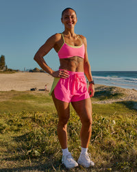Woman wearing Accelerate 3" High-Rise Running Short - Lime Glo-Sugar Plum | Model:Chelsea | Size:XS | Thumbnail Index: 1