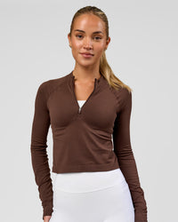 Woman wearing AeroFLX+ Long Sleeve Skimmer Half Zip - Hot Chocolate/Hot Chocolate | Model:Issy | Size:XS | Thumbnail Index: 0