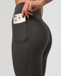 Woman wearing Fusion Ultra High-Rise 7/8 Legging Pockets - Onyx | Model:Issy | Size:XS | Thumbnail Index: 1