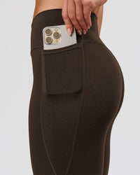Woman wearing Fusion V-Contour High-Rise Flared Petite Legging Pockets - Ground Coffee | Model:Issy | Size:XS | Thumbnail Index: 4