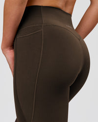 Woman wearing Fusion V-Contour High-Rise Flared Petite Legging Pockets - Ground Coffee | Model:Issy | Size:XS | Thumbnail Index: 5