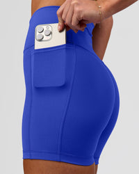 Woman wearing Fusion V-Contour Ultra High-Rise 4" Short Pockets - Power Cobalt | Model:Issy | Size:XS | Thumbnail Index: 2