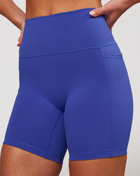 Woman wearing Fusion V-Contour Ultra High-Rise 6" Short Pockets - Power Cobalt | Model:Issy | Size:XS | Thumbnail Index: 1