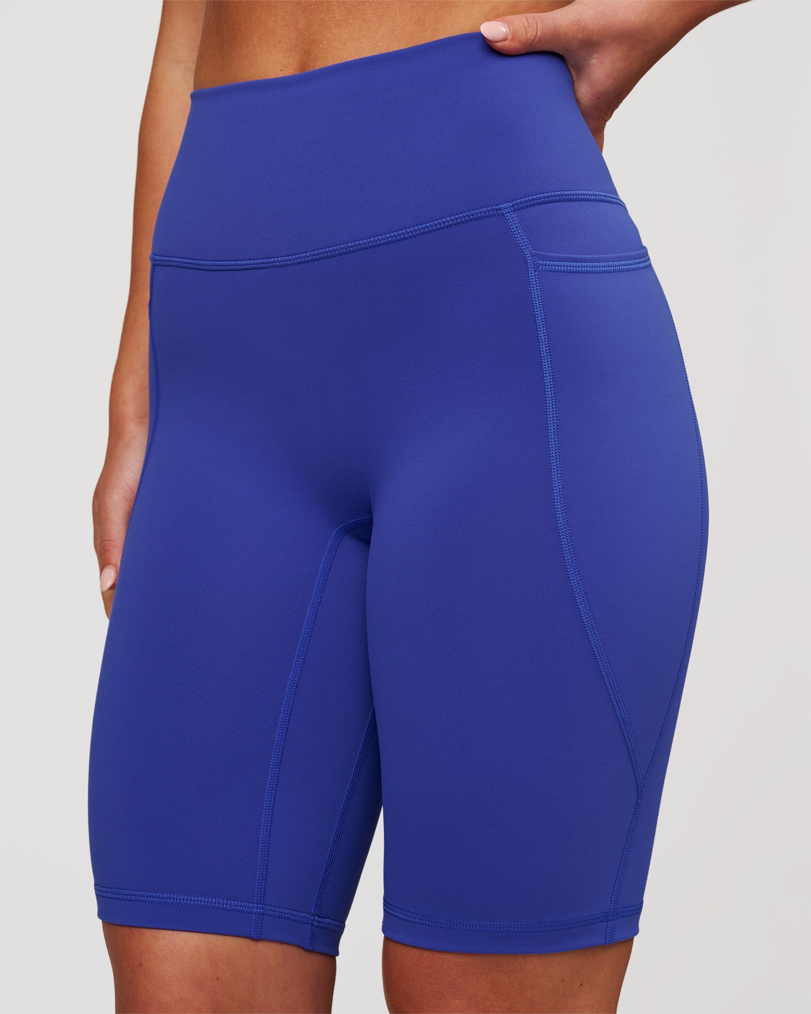 Woman wearing Fusion V Contour Ultra High-Rise 9" Short Pockets - Power Cobalt | Model:Issy | Size:XS