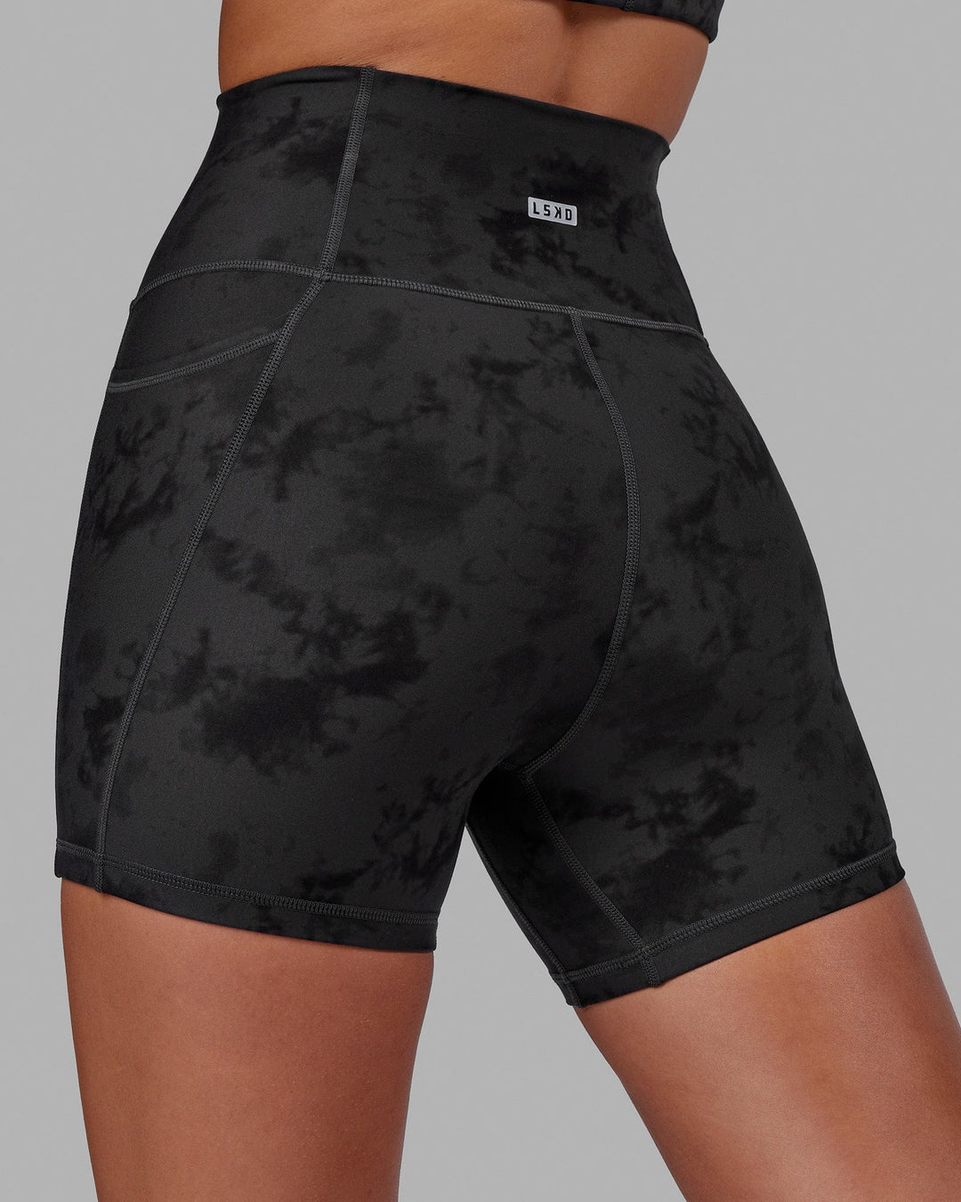 Woman wearing Fusion Ultra High-Rise 4" Short Pockets - Black Tie-Dye | Model:Milly | Size:S