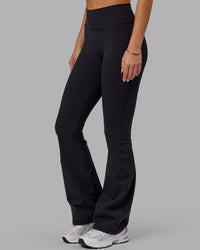 Woman wearing Fusion Ultra High-Rise Flared Legging Pockets - Black | Model:Milly | Size:S